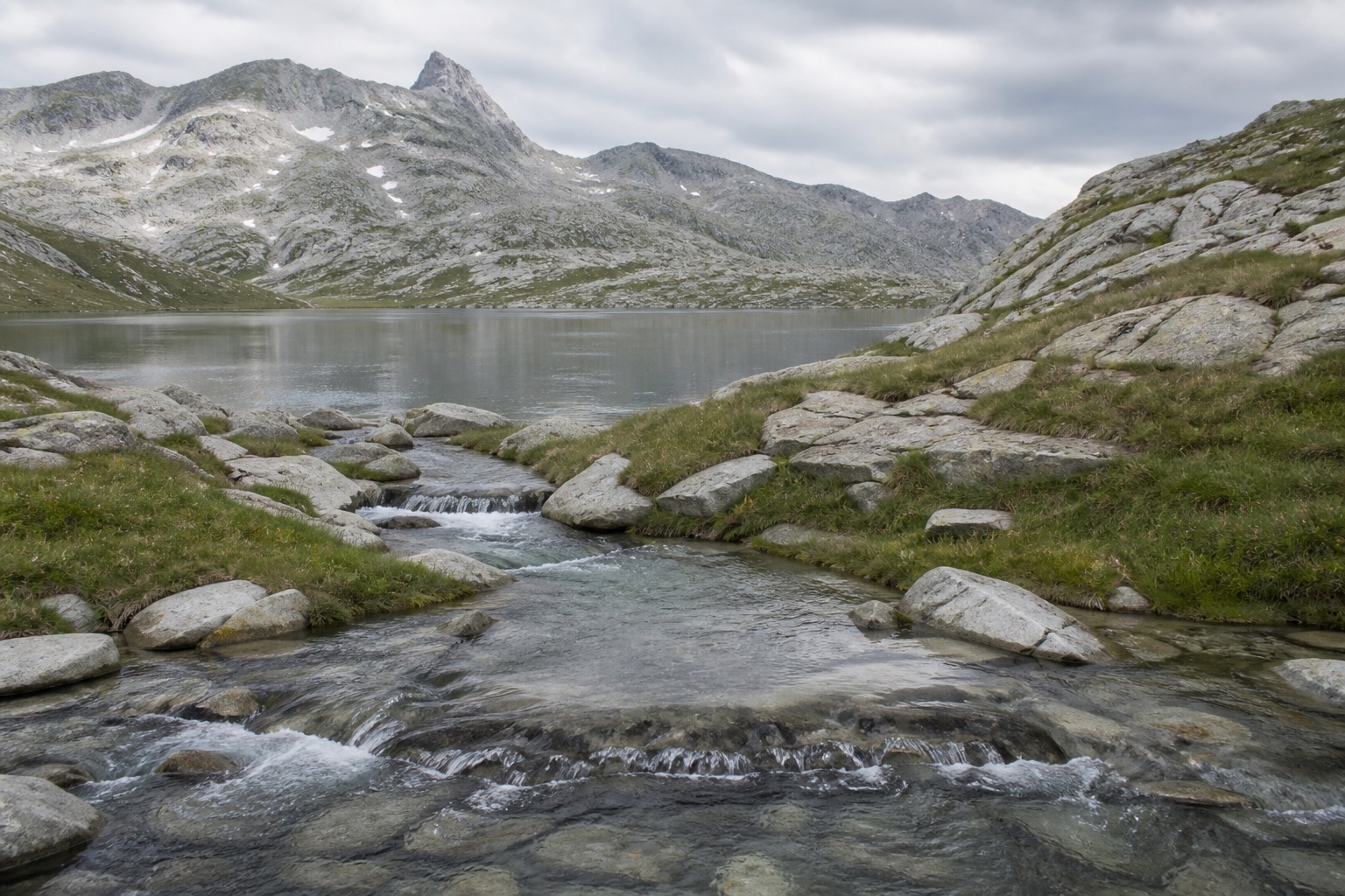 Klarer Alpenbach vor einem ruhigen Bergsee